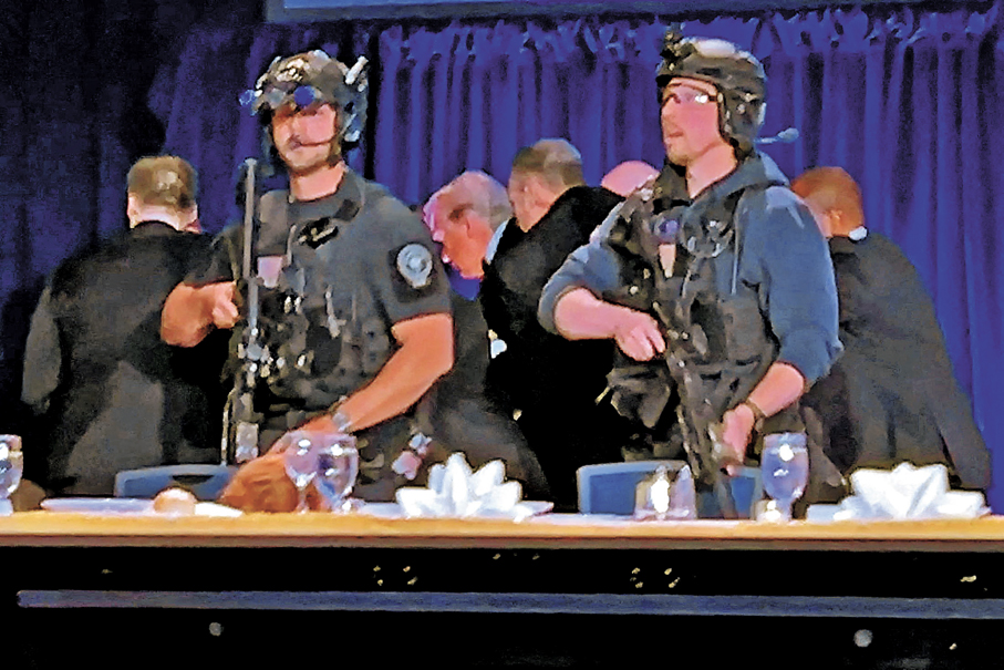 ●保安人員上台將特朗普（中）和梅拉尼婭帶離主席台，特勤局人員在旁持槍戒備。 路透社