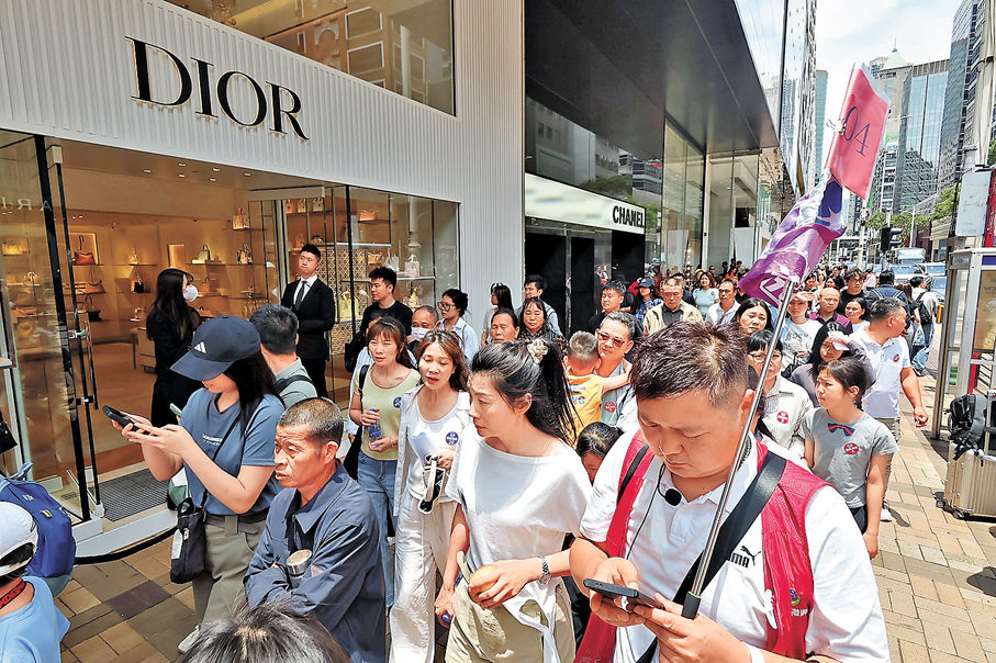 ●精品名店街頭，遊客摩肩接踵，旅行團舉旗穿梭。香港文匯報記者涂穴  攝