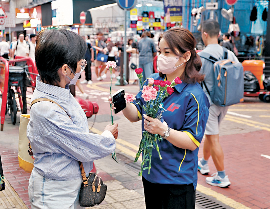 ●有連鎖店舖職員在街頭向女士送上鮮花。香港文匯報記者黃艾力  攝
