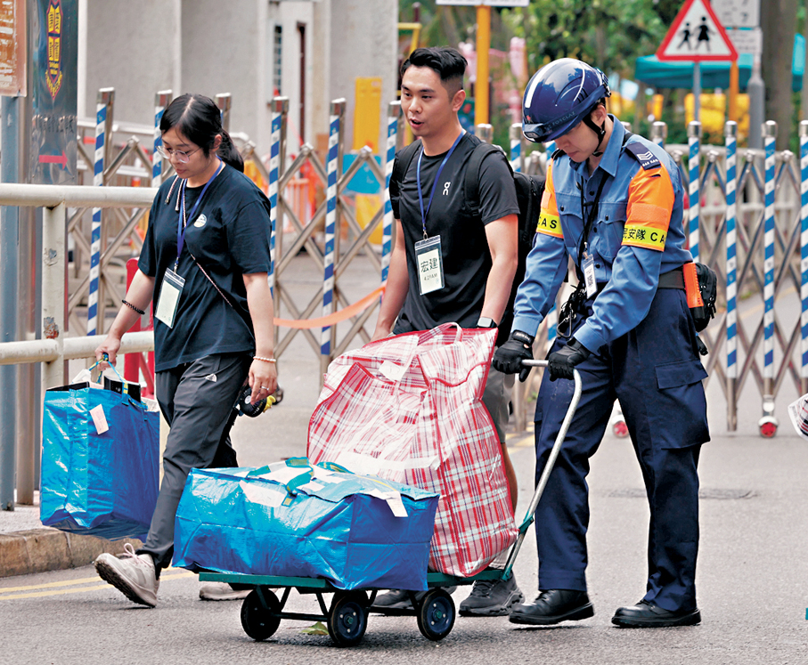 ●李家超表示，許多公務員樂意參與支援宏福苑居民上樓執拾工作。圖為民安隊隊員協助宏福苑居民搬物品落樓。 資料圖片
