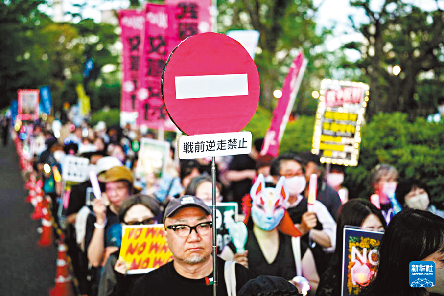 ●在東京的國會議事堂前，日本民眾手持標語參加抗議集會。 新華社