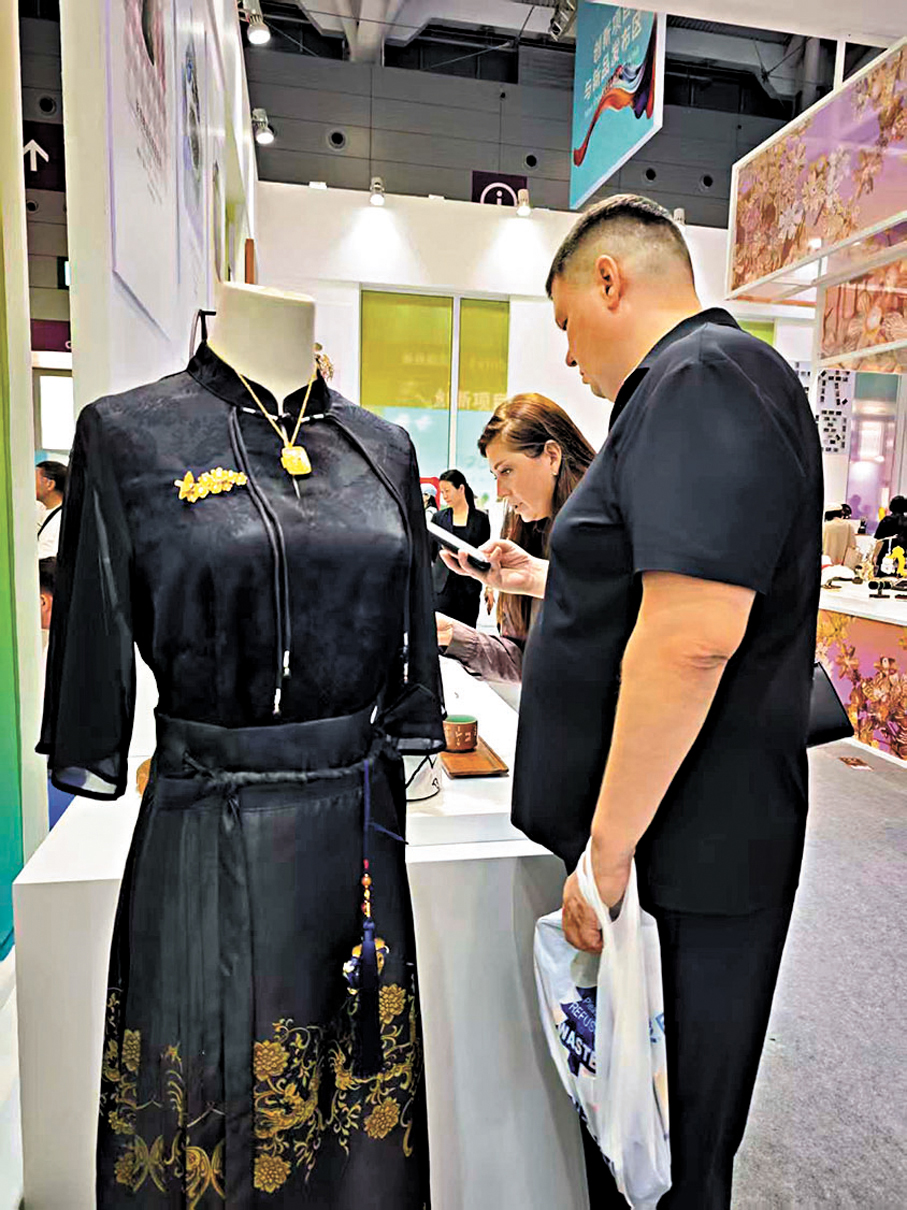 ●外國展商觀賞中國服飾。香港文匯報記者李薇  攝
