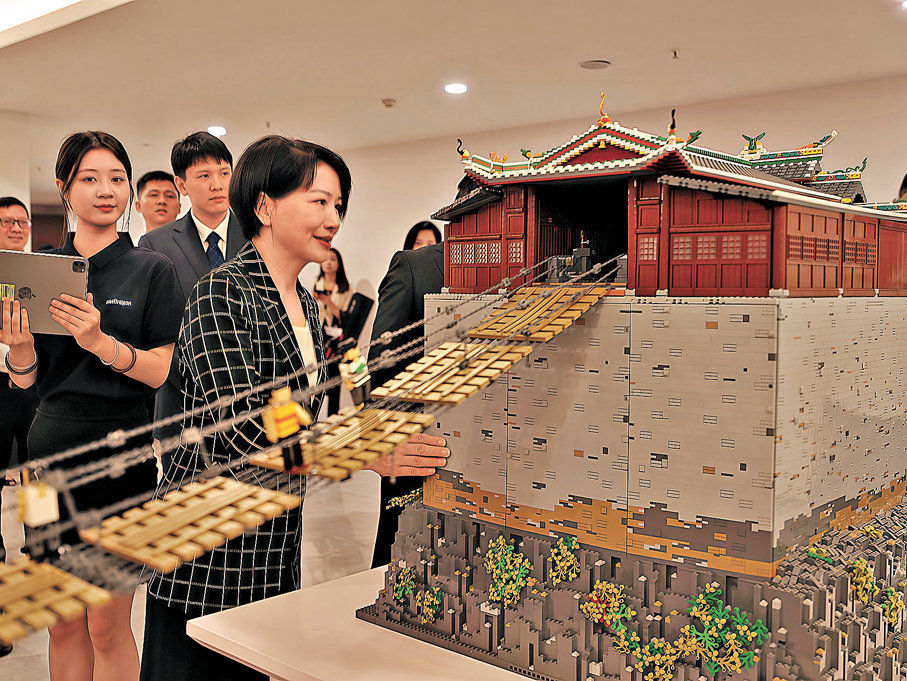 ●江西省委常委、宣傳部部長盧小青（右一）參觀由網龍網絡公司搭建的「飛奪瀘定橋」積木互動沙盤。