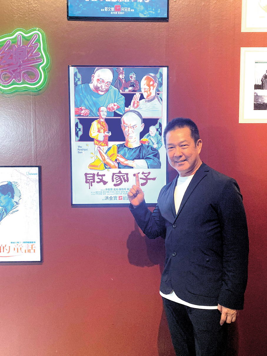 ●元彪與自己有份出演的電影海報合影。 香港電影資料館供圖
