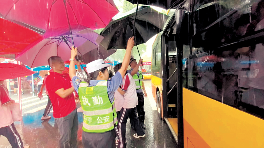 ●開平市一考點附近，執勤民輔警撐傘護航考生。   香港文匯報廣州傳真