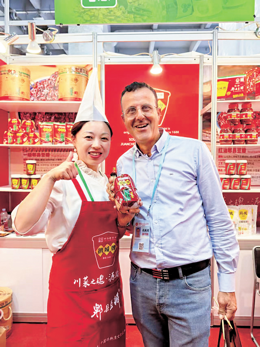 ●海外消費者手拿郫縣豆瓣與工作人員合影。
