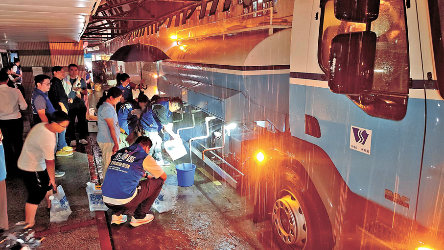 ●居民入夜後到水車取水。香港文匯報記者鄺福強  攝