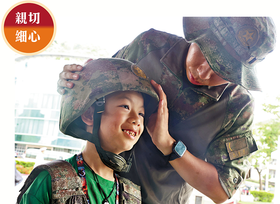 ●軍人細心地為男孩調整迷彩頭盔，男孩臉上洋溢笑容。香港文匯報記者萬霜靈  攝