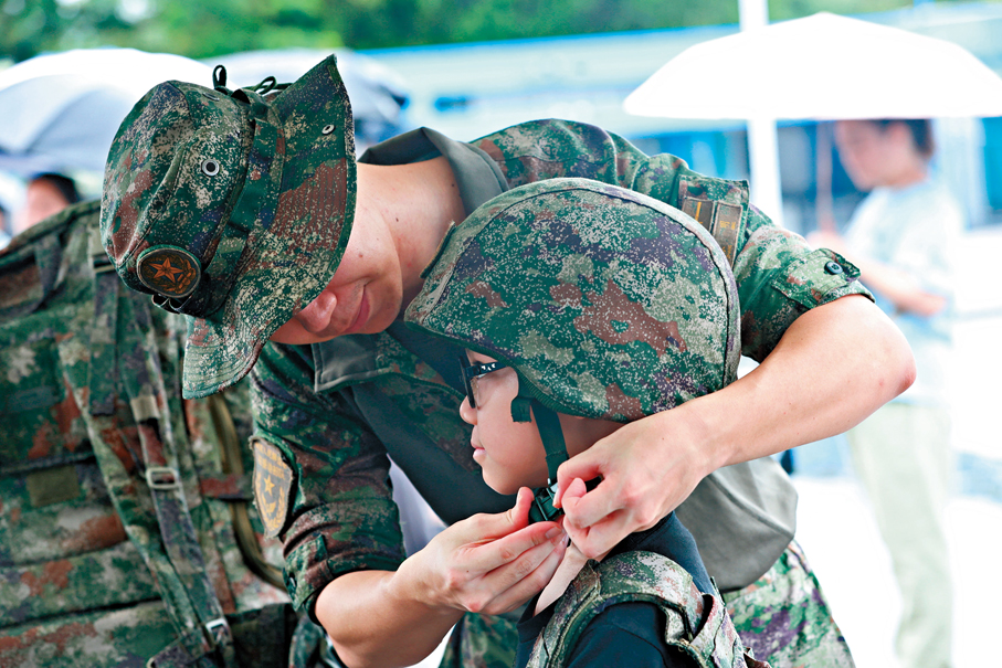 ●石崗軍營周日開放日，官兵細心地為小朋友戴上頭盔。 香港文匯報記者萬霜靈  攝