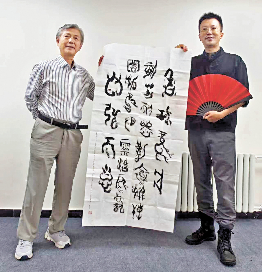 ●魏運成教授（左）持書法作品與梁家僖合影。   作者供圖