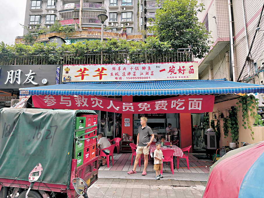 ●本地餐店掛出「參與救災人員免費吃麵」標語。 香港文匯報記者韓毅  攝