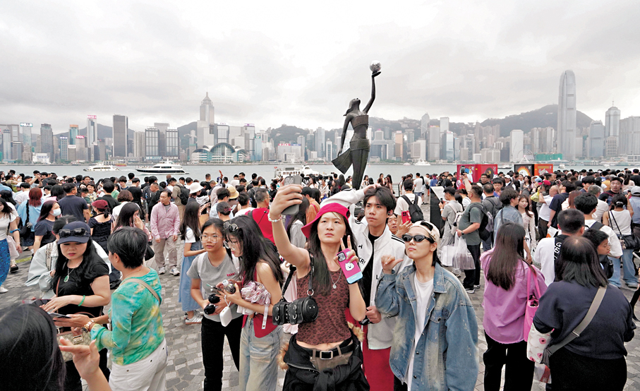 ●香港資本市場活動蓬勃、內地旅客增長、人工智能「超級周期」帶動貿易增長等，驅動樓市與消費氣氛復甦。圖為在維港開心打卡的內地旅客。 資料圖片