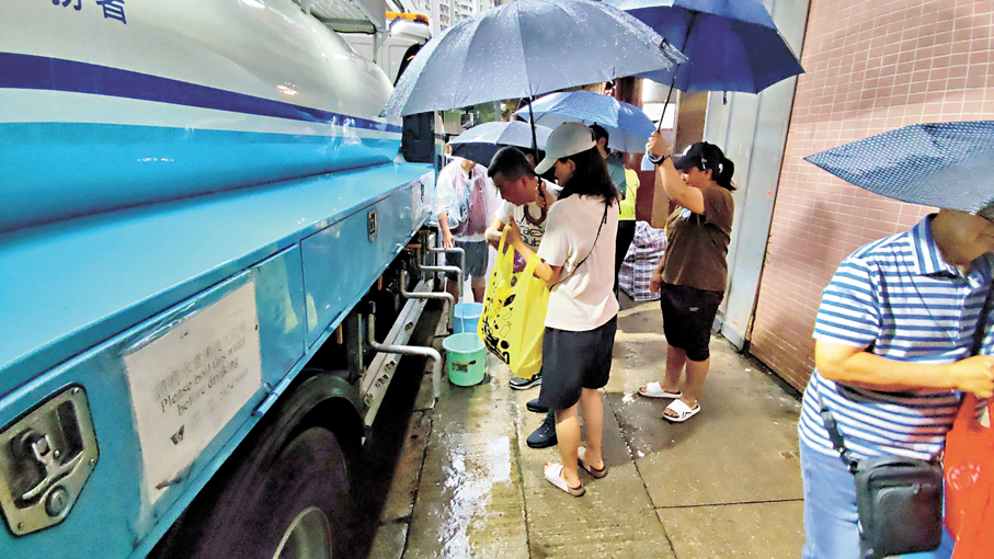 ●昨早繼續有受影響的居民落樓冒雨取水。 香港文匯報記者林兆崙  攝