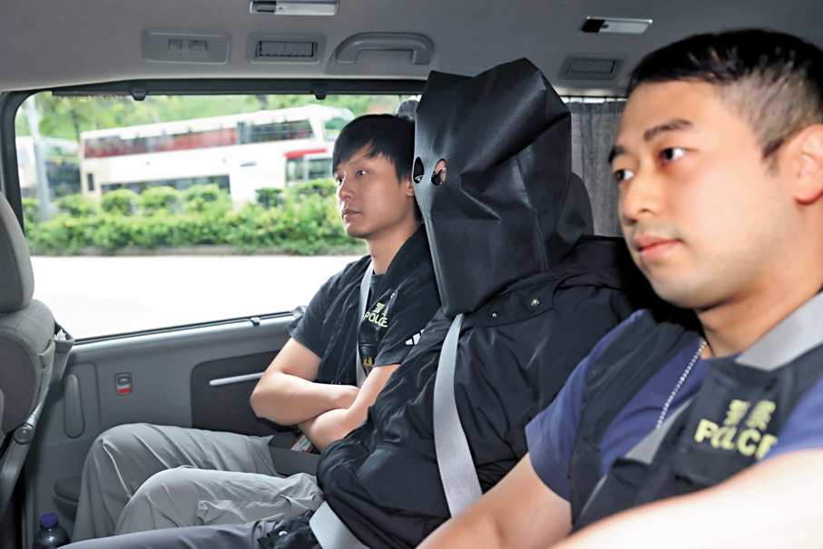 ●其中一名疑犯黑布蒙頭由探員押返警署扣查。香港文匯報記者劉友光  攝