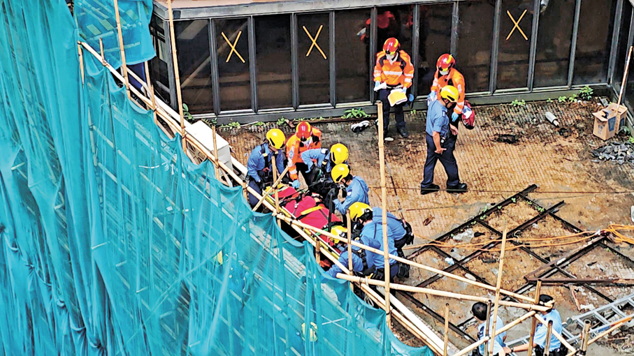 ●救援人員把墮樓的地盤安全經理運送落地面。   香港文匯報記者劉友光  攝