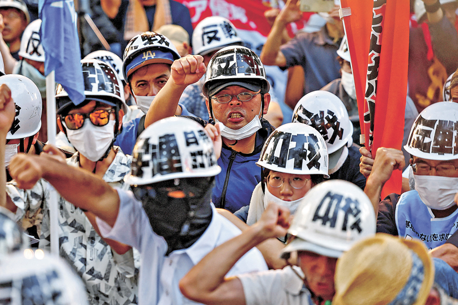 ●廣島民眾戴上寫有反戰等字眼的頭盔集會，抗議高市政府一系列擴軍圖謀。 路透社