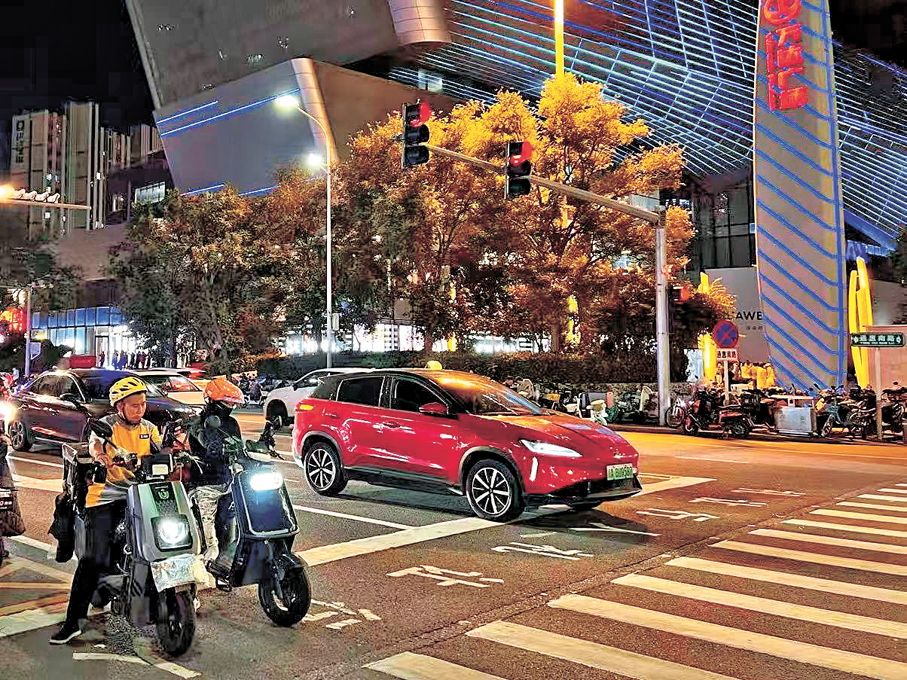 ●美團上線外賣騎手「紅燈停錶」功能，已在北京多區的部分道路進行試點路測。圖為夜晚的北京，外送員正在等紅燈。
