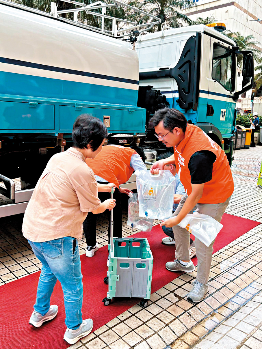 ●關愛隊隊員協助受影響居民盛載食水。作者供圖