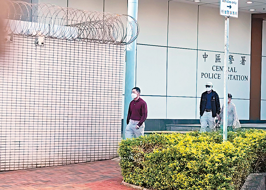 ●被捕姓譚男子（紅衣者）離開中區警署。香港文匯報記者鄺福強  攝
