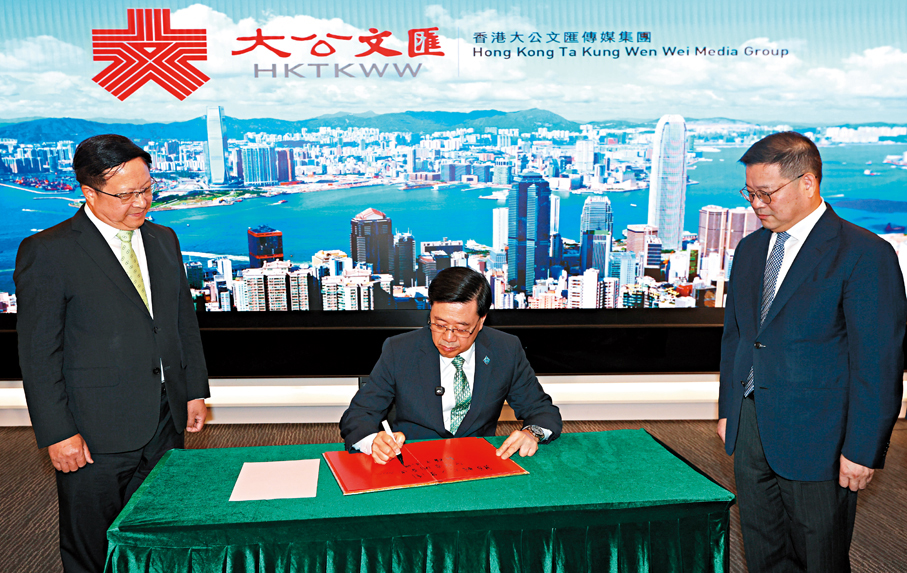 ●香港特區行政長官李家超（中）在紀念冊上題字。 香港文匯報記者曾興偉  攝