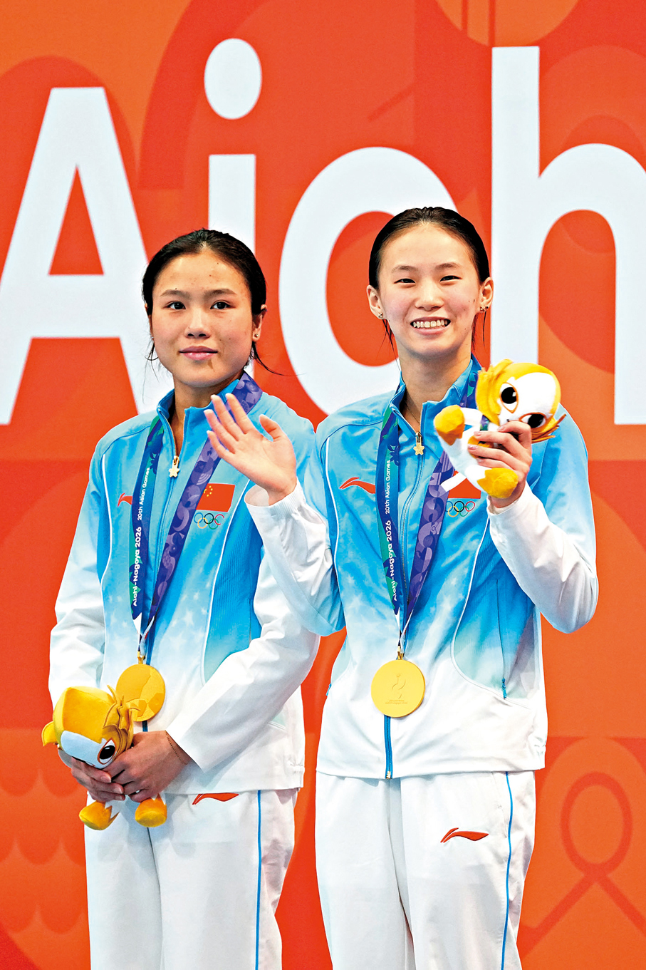 ●在女子雙人10米台奪金的陳芋汐（右）與盧為，領獎時向觀眾揮手致意。 中新社