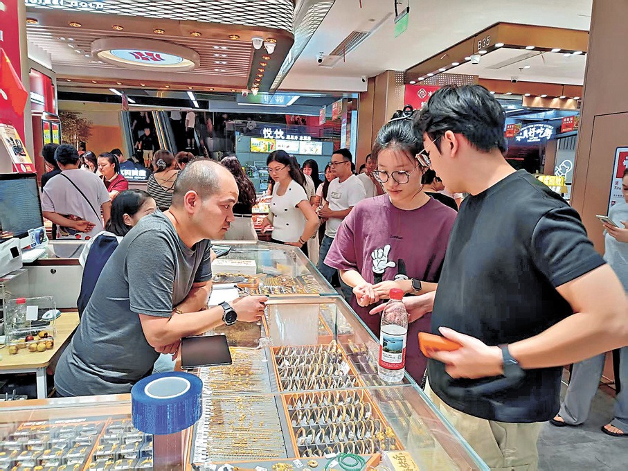 ●國慶節婚慶類金飾需求旺，方先生（左）表示，近幾日每天銷量較平時增長一兩倍。 香港文匯報記者李昌鴻  攝