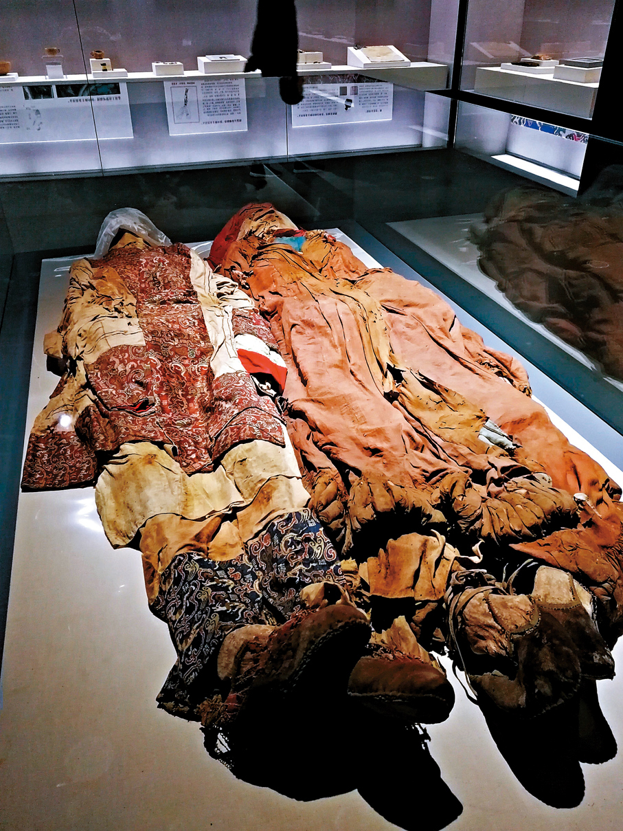 ●圖為新疆博物館展出的「萬世如意」銘文錦袍出土時的情形復原。