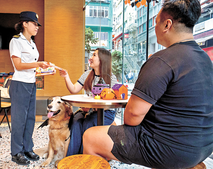 ●食環署人員到獲准食肆向攜狗顧客派發宣傳單張，提醒他們攜狗外出用膳時須守法依規。政府新聞處