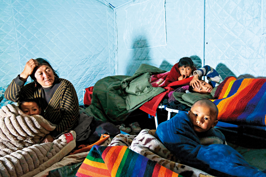 ●10月23日深夜，西藏巴青縣幫玉囊村安置區帳篷內，村民吉美和她的孫兒孫女們準備入睡。 中新社