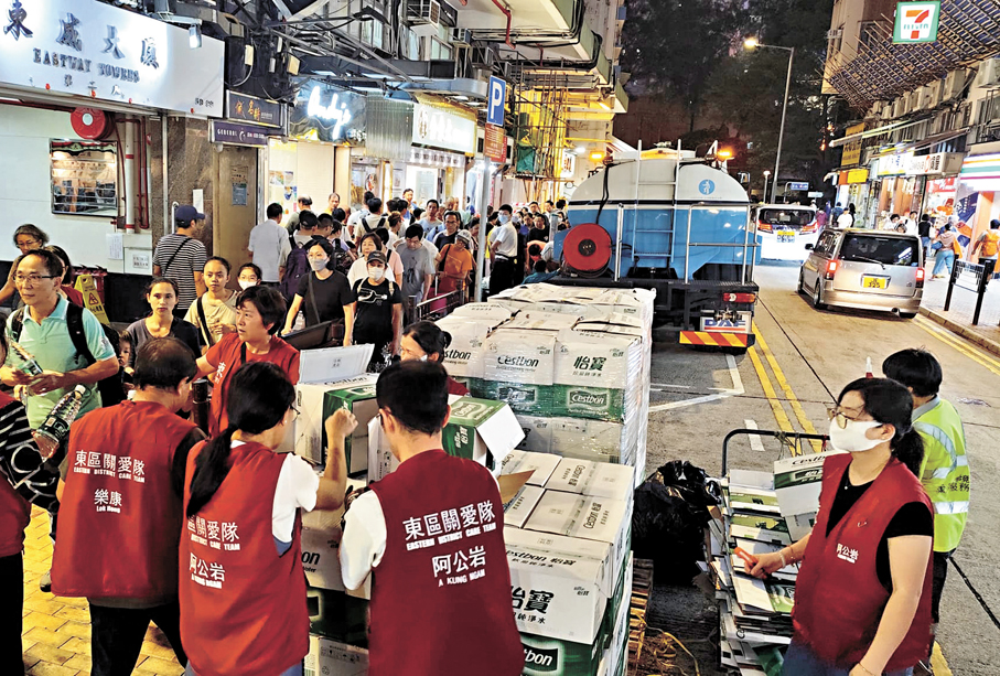 ●關愛隊隊員昨晚向受影響居民派樽裝水。 香港文匯報記者鄺福強  攝